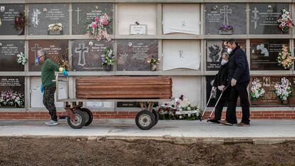 Un operario de un cementerio de València traslada un féretro seguido por los familiares de la víctima durante un entierro en abril de 2020, en plena pandemia.