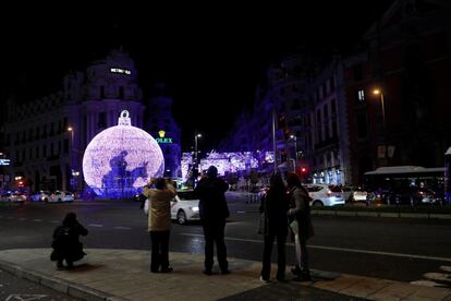 Varias personas toman fotografías de las luces navideñas de la capital, en la calle de Alcalá, al fondo, la Gran Vía.