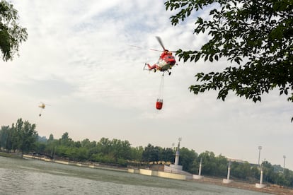 Helicópteros cargan con agua para ayudar en las tareas de contención del incendio en Tres Cantos, Madrid, este martes.