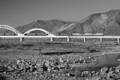 <p>Un tren tibetano cruzando un puente sobre el río Kyuchu en su camino hacia Lhasa. El ferrocarril a Tíbet es uno de los mayores proyectos de ingeniería chino. Se creía que nadie podría construir una línea más allá de la meseta de Qinghai, y menos todavía uno que llegase hasta Tíbet. Era demasiado inhóspito y frío, y no había oxígeno. Incluso los mejores ingenieros de túneles suizos concluyeron que era imposible perforar a través de la roca y el hielo de la cordillera de Kunlun.  	</p>	
<p>A más o menos un metro de profundidad, la superficie era una gruesa capa de permafrost; por encima de ella, había una capa de hielo que se derrite y se vuelve a congelar dependiendo de las estaciones y según sale y se pone el sol. ¿Cómo podría alguien construir una vía sobre eso? ¿Y cómo podría establecerse un servicio regular en una zona plagada de tormentas de arena en verano y de ventisca en invierno? Finalmente, tres años antes de lo previsto, en julio de 2006, los ingenieros chinos construyeron el tramo final de la vía en una línea que va hasta Lhasa cruzando el techo del mundo. El primer año, el tren transportó a 1,5 millones de personas, principalmente hombres de negocios chinos y turistas. </p>  


