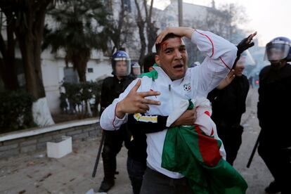 Un hombre, herido durante las protestas, es detenido por miembros de la policía antidisturbios.