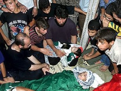 Un grupo de palestinos observan los restos un niño de dos meses y otro de tres años que murieron en el ataque de ayer.
