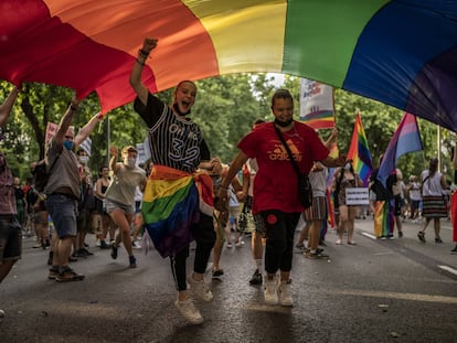 Dos jóvenes pasaban debajo de una bandera multicolor durante la manifestación del Orgullo en Madrid, el 3 de julio de 2021.