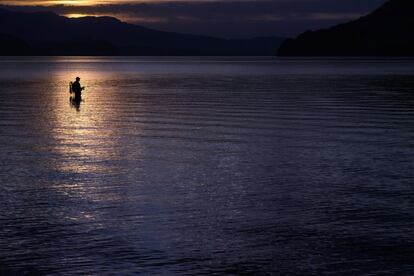 Un pescador pesca en el lagoThun durante la puesta de sol en el Oberland bernés, Suiza.