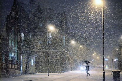 Una mujer cruza una calle nevada de Londres. 