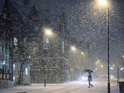 Una mujer cruza una calle nevada de Londres. 