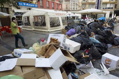 Un vecino pasa junto a la basura acumulada en una plaza del centro de M&aacute;laga.