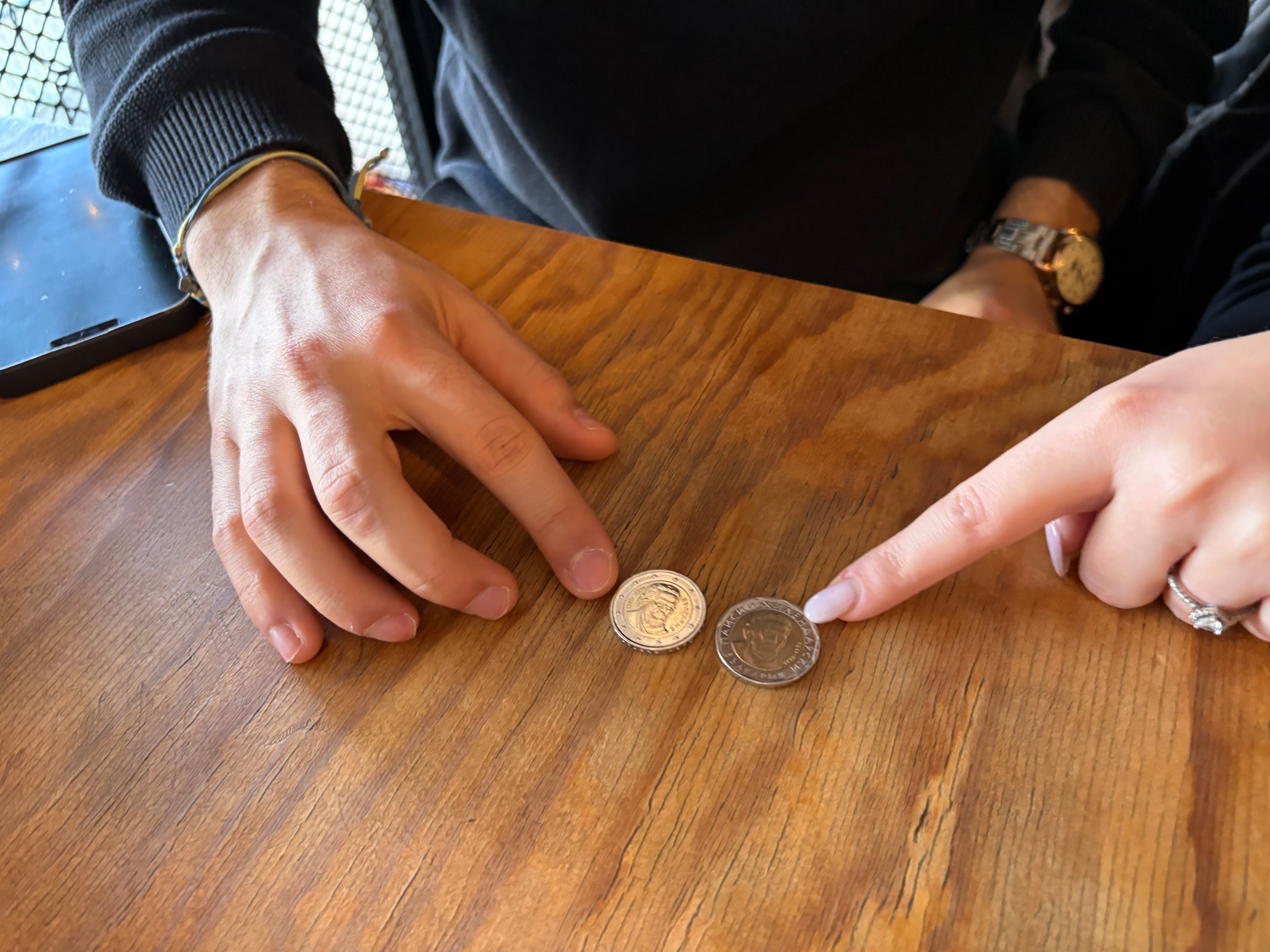 Dos jóvenes muestran una moneda euro búlgara (izquierda) y otra, la leva antigua (derecha), ambas parecidas