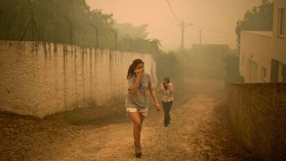 Dos mujeres se cubren la boca con pañuelos mientras en los incendios en Portugal de 2017.