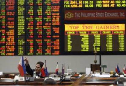 Un agente de bolsa filipino gesticula mientras la pantalla electrónica muestra el valor que han alcanzado las acciones en la Bolsa de Valores de Manila, en el distrito financiero de Makati. EFE/Archivo