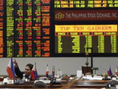 Un agente de bolsa filipino gesticula mientras la pantalla electrónica muestra el valor que han alcanzado las acciones en la Bolsa de Valores de Manila, en el distrito financiero de Makati. EFE/Archivo