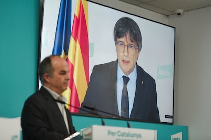 El secretario general de Junts, Jordi Turull (a la izquierda), y el presidente de Junts, Carles Puigdemont (en pantalla), el martes en rueda de prensa.