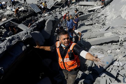 Personal de emergencias y voluntarios buscan supervivientes entre los escombros de un edificio derrumbado tras un bombardeo israelí, en Jan Yunis. 
