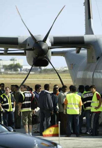 Policías españoles acompañan a los inmigrantes a uno de los aviones que les llevarán a España desde Malta.