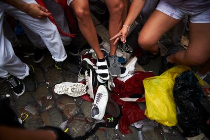 Varias personas recolectan zapatillas perdidas después del chupinazo de San Fermín 2022. 