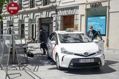 Un taxista con mascarilla deja a un pasajero en una calle de Madrid.