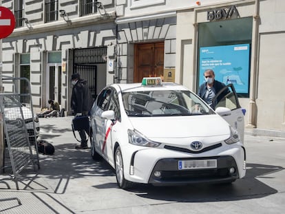 Un taxista con mascarilla deja a un pasajero en una calle de Madrid.