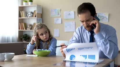 Una niña mira con recelo a su padre mientras trabaja.