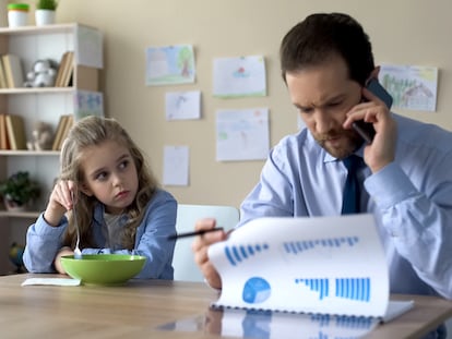 Una niña mira con recelo a su padre mientras trabaja.