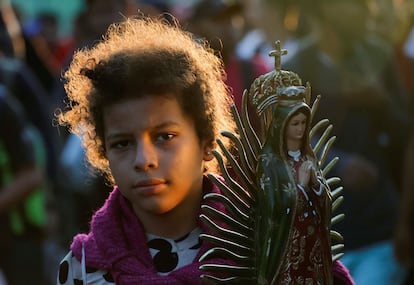 Darlyn Mejía, migrante venezolana, lleva una figura de la Virgen de Guadalupe mientras camina con su familia en caravana en Tapachula.