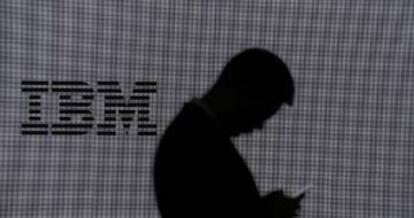 Un hombre revisa su teléfono móvil en un stand de IBM.