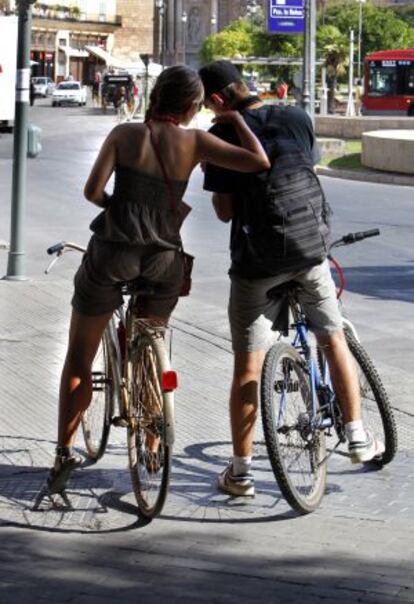 Dos turistas extranjeros recorren Valencia en bicicleta.