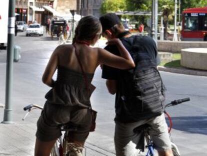 Dos turistas extranjeros recorren Valencia en bicicleta.