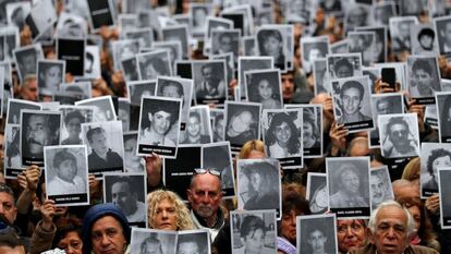 Cientos de personas levantan las fotografías de las 85 víctimas del atentado contra la mutua AMIA en 1994, durante una concentración en la sede de la Asociación de Mutuales Israelitas Argentinas (AMIA), en el barrio porteño de Once, en Buenos Aires (Argentina).