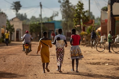 Tres jóvenes, una de ellas con su bebé en las espaldas, caminan por una calle del pueblo de Jurú, en Ruanda, en junio de 2023.