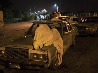 Um homem dorme sobre seu carro enquanto espera por gasolina em Maracaibo.