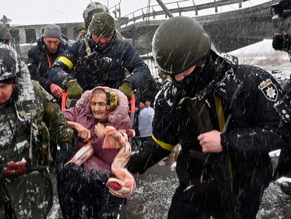 Varios soldados ucranios ayudan a una anciana en Irpin.