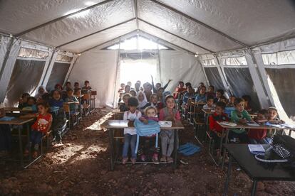 Fotografia tirada em um acampamento improvisado em Atmeh, no norte da cidade síria de Idlib, em 30 de setembro de 2019. As crianças assistem a uma aula de árabe em sua tenda de campanha transformada em escola. Em Atmeh, as famílias buscaram refúgio sob olivais e galpões em condições precárias. A maioria das crianças não tinha tido frequentado uma escola durante anos.