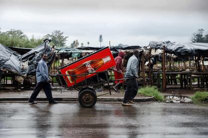 Tres hombres portan un frigorífico mientras abandonan la ciudad de Harare, desierta tras las protestas violentas debido al incremento en el precio del combustible.