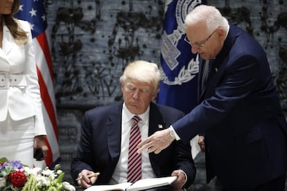 El presidente estadounidense Donald Trump firma en el libro de visitas de la residencia presidencial en Jerusalén, junto a su mujer y primera dama Melania Trump y al presidente de Israel Reuven Rivlin.