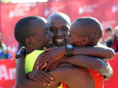 Los kenianos Kipchoge, Kittwara y Chumba se abrazan tras cruzar la meta del maratón de Chicago.