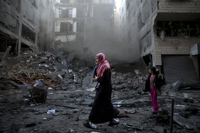 Una familia palestina camina entre los escombros de un edificio residencial destruido por los misiles israelíes, en Gaza.