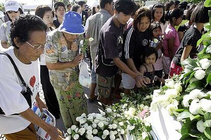 Un grupo de personas coloca flores en Ban Nam Khem (Tailandia) en un monumento en memoria de las víctimas del maremoto.