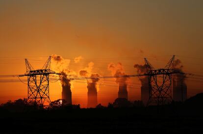 Postes de electricidad se ven delante de las torres de refrigeración de la central térmica de Lethabo, cerca de Sasolburg, en la provincia norteña del Free State (Sudáfrica). 