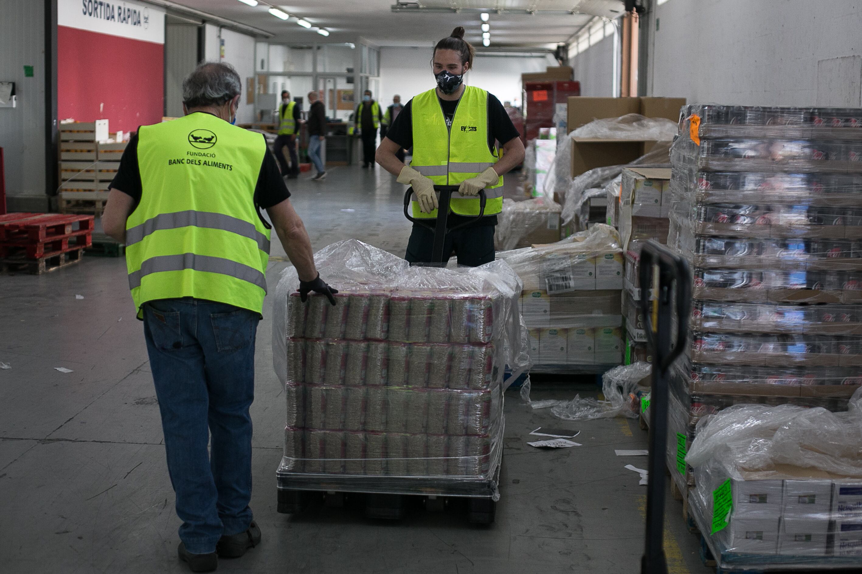 Dos voluntarios colocan productos en un almacén del Banco de Alimentos. 