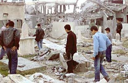 Varios palestinos observan los daños causados en un cementerio de la ciudad de Gaza por los bombardeos israelíes.