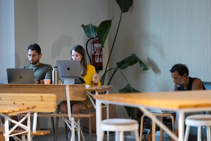 Jóvenes trabajando en el interior de la cafetería del espacio de 'coworking' Itnig del barrio del Poblenou de Barcelona.