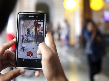 Un home intenta caçar un 'pokémon' després d'haver-lo localitzat.