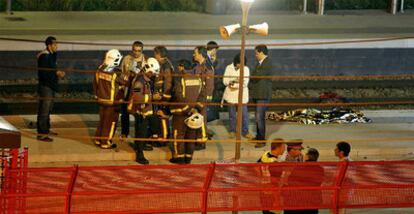 Personal de bomberos y de los servicios de emergencias junto a uno de los cuerpos, anoche en la estación de Castelldefels Playa.