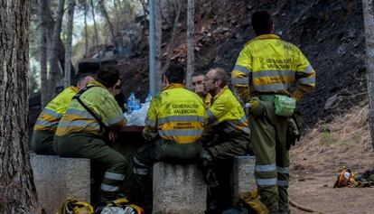 Los bomberos forestales descansan durante los trabajos de extinci&oacute;n del incendio de Gilet.