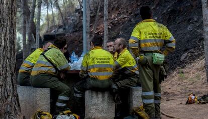 Los bomberos forestales descansan durante los trabajos de extinción del incendio de Gilet.