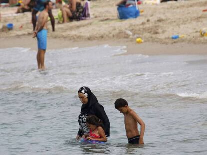 Una mujer en burkini con sus hijos en la playa de Marsella.