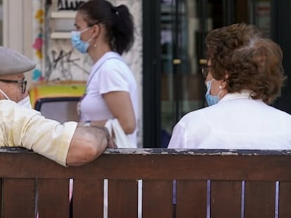 Una pareja de ancianos con mascarilla sentada en un banco en Madrid.