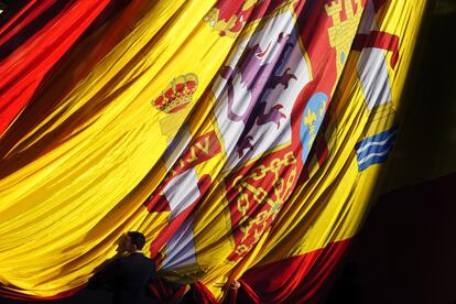 Un oficial ayuda a desplegar la bandera nacional durante la celebración del 33 aniversario de la Constitución.