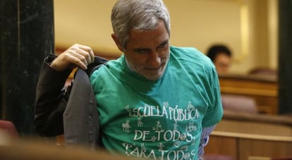 El diputado de IU, Gaspar Llamazares, se quita la chaqueta sobre la camiseta verde con el lema "Escuela pública de todos para todos".