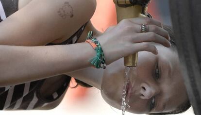 Una turista se refresca en la fuente de Canaletas, en la Rambla de Barcelona.